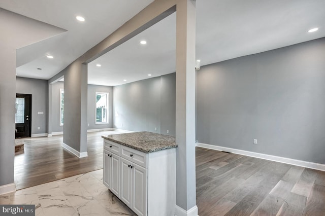 kitchen featuring light hardwood / wood-style flooring, white cabinets, and light stone countertops