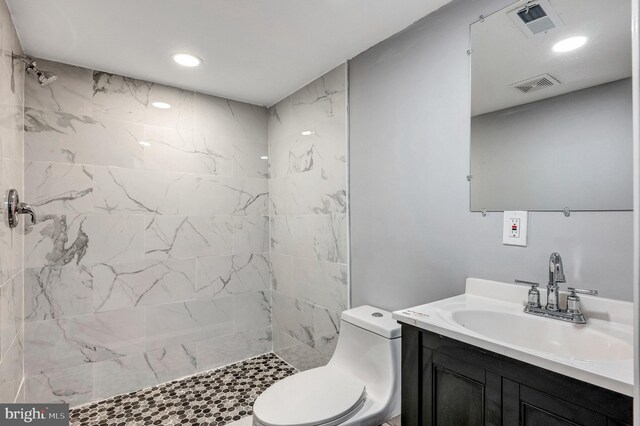 bathroom featuring toilet, a tile shower, and vanity