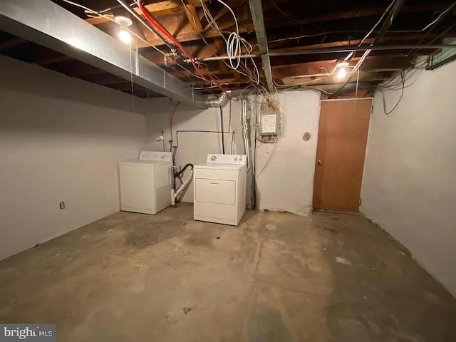 unfinished below grade area featuring electric panel and separate washer and dryer