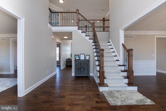 stairway featuring hardwood / wood-style flooring, crown molding, and a towering ceiling