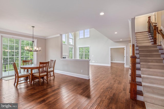 dining room with a towering ceiling, a notable chandelier, crown molding, and dark hardwood / wood-style floors