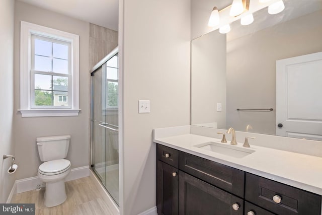 bathroom featuring a shower with shower door, toilet, and vanity