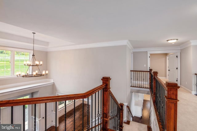 corridor featuring baseboards, wood finished floors, an inviting chandelier, crown molding, and an upstairs landing