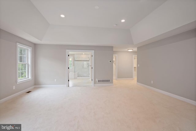 spare room with a raised ceiling, visible vents, and baseboards