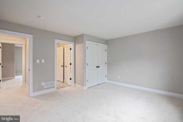 unfurnished bedroom featuring baseboards, visible vents, and light colored carpet