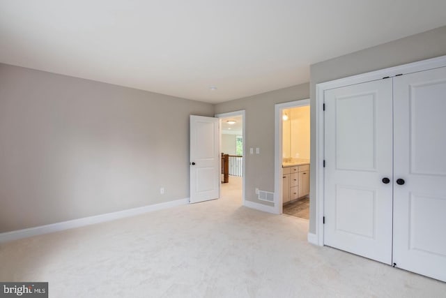 unfurnished bedroom featuring a closet, light colored carpet, visible vents, and baseboards