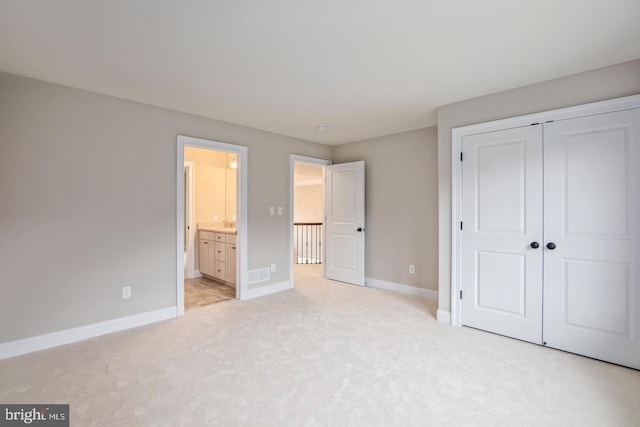 unfurnished bedroom with light carpet, visible vents, baseboards, connected bathroom, and a closet