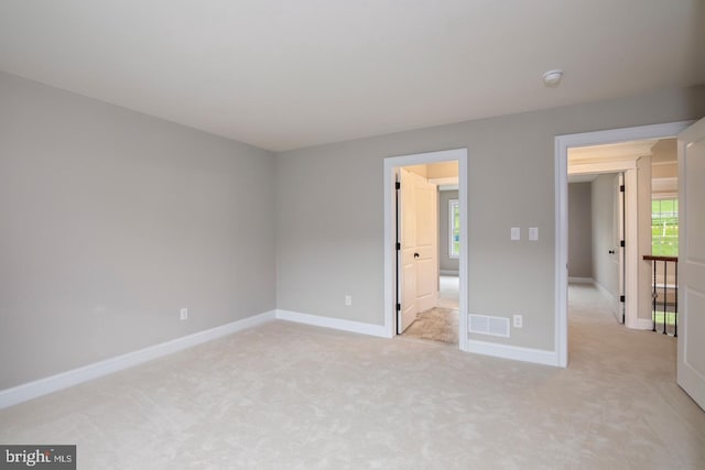 unfurnished bedroom with light colored carpet, visible vents, and baseboards