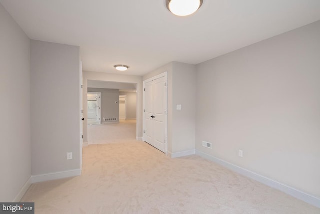 empty room with light carpet, visible vents, and baseboards