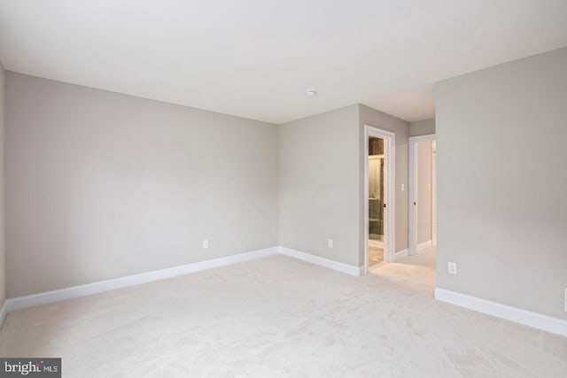 unfurnished room featuring light colored carpet and baseboards