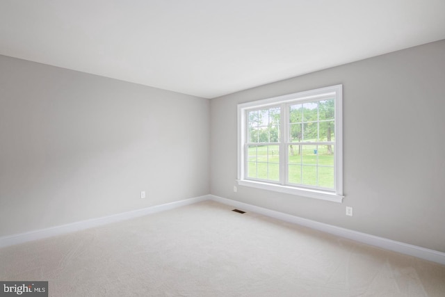 carpeted spare room featuring visible vents and baseboards