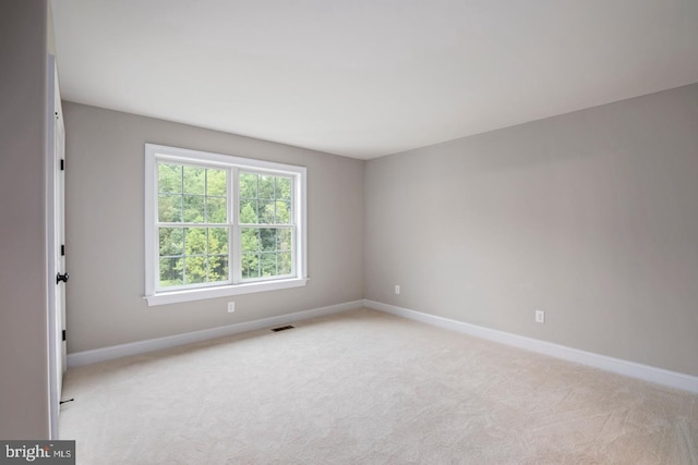 spare room featuring light carpet, baseboards, and visible vents