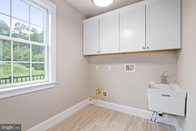 laundry room with sink, light hardwood / wood-style flooring, washer hookup, and cabinets