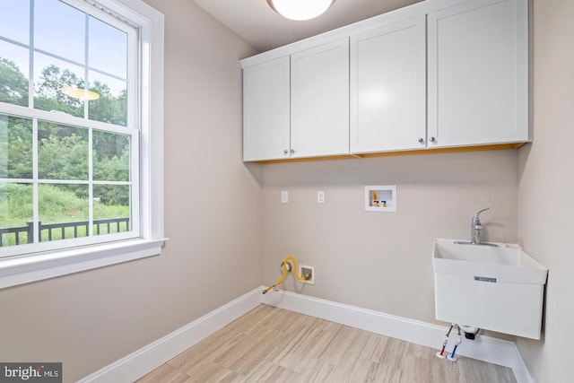 clothes washing area featuring a sink, hookup for a washing machine, baseboards, and cabinet space