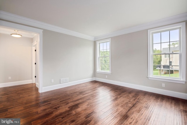 spare room featuring dark wood-style floors, visible vents, ornamental molding, and baseboards