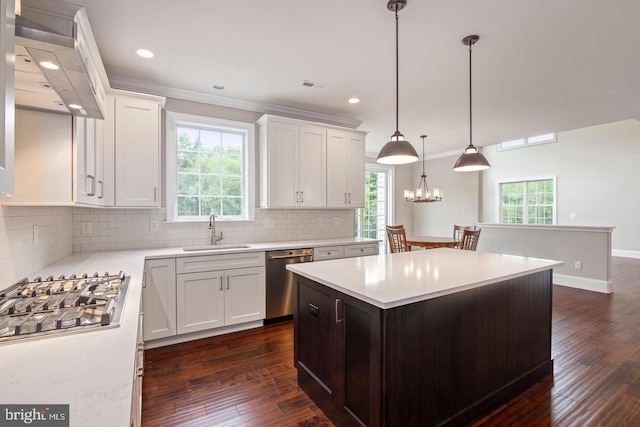 kitchen featuring appliances with stainless steel finishes, a center island, light countertops, and a sink