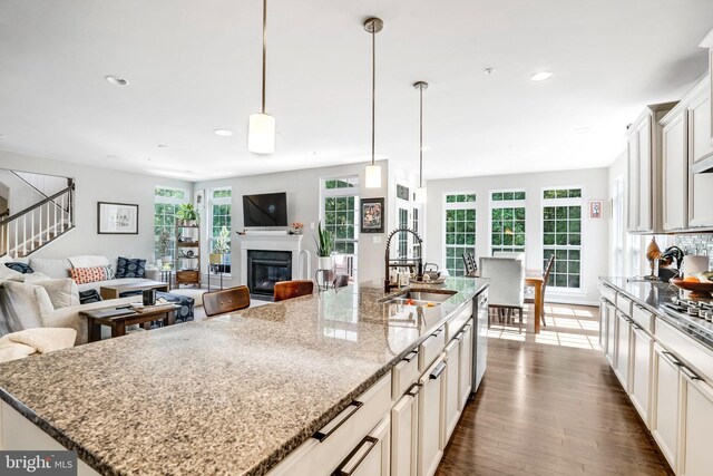 kitchen featuring hanging light fixtures, sink, a kitchen island with sink, stainless steel appliances, and dark hardwood / wood-style floors