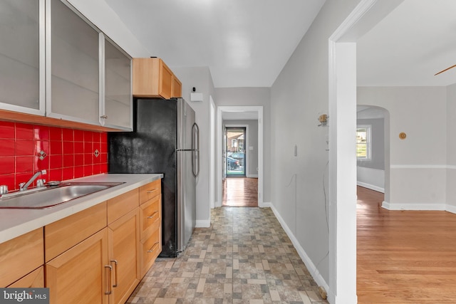 kitchen featuring tasteful backsplash, stainless steel fridge, light hardwood / wood-style flooring, and sink