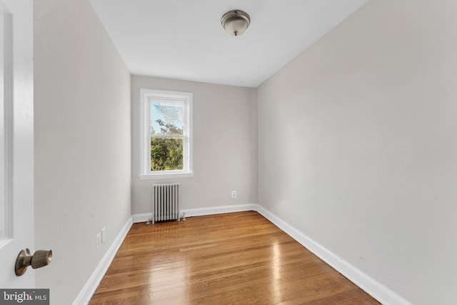 empty room featuring radiator heating unit, baseboards, and wood finished floors