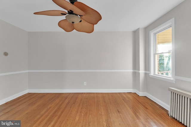 spare room with ceiling fan, radiator, and light wood-type flooring