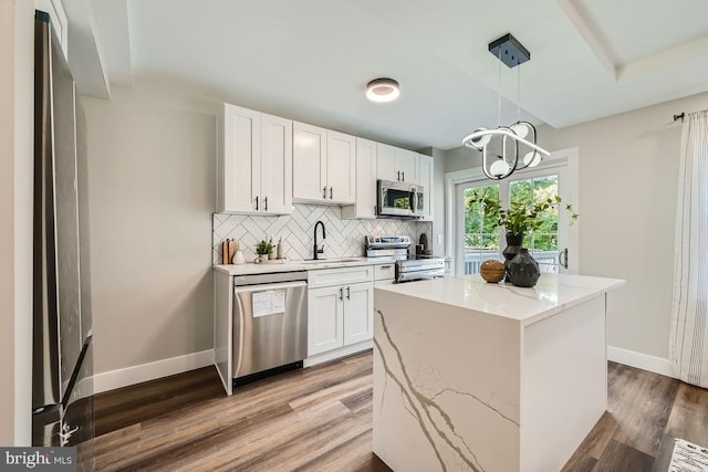 kitchen featuring white cabinets, appliances with stainless steel finishes, pendant lighting, and sink