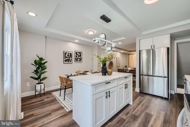 kitchen with dark hardwood / wood-style floors, stainless steel fridge, hanging light fixtures, a center island, and white cabinets