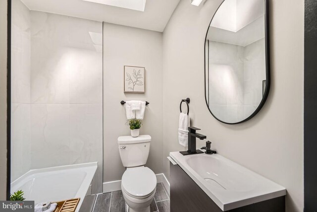 bathroom with vanity, toilet, hardwood / wood-style flooring, and a washtub