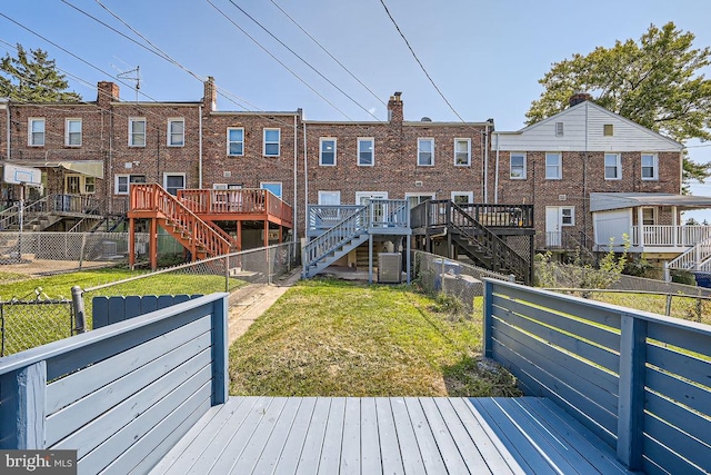 rear view of property featuring a lawn, a deck, and central AC unit