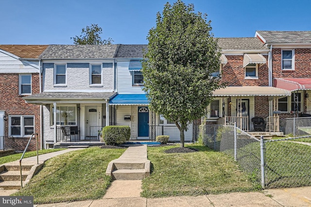 townhome / multi-family property featuring a porch, a front lawn, a shingled roof, and a fenced front yard