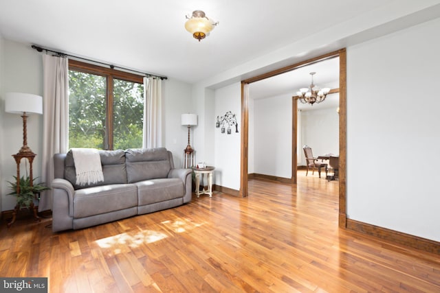 living room with an inviting chandelier, baseboards, and light wood-style floors