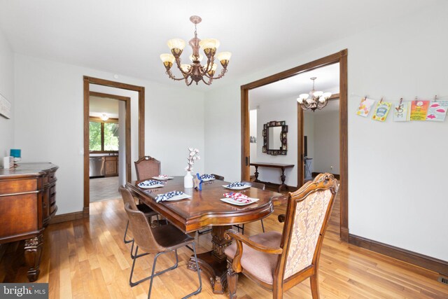 dining room with a chandelier, baseboards, and light wood-style floors