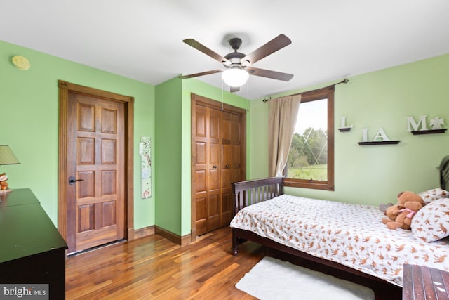 bedroom featuring ceiling fan, wood finished floors, a closet, and baseboards