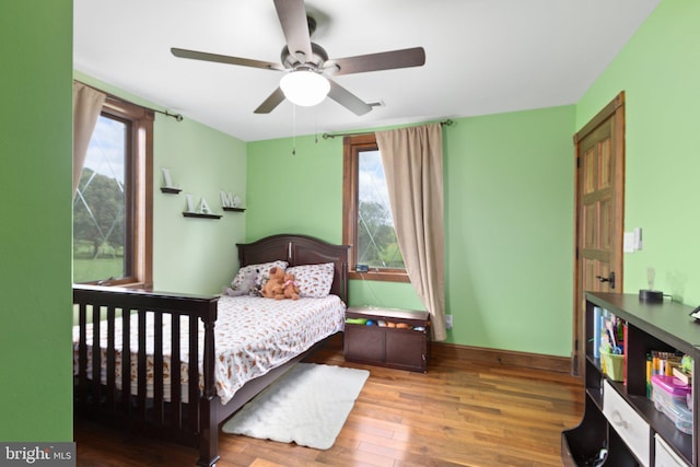 bedroom with multiple windows, a ceiling fan, baseboards, and wood finished floors