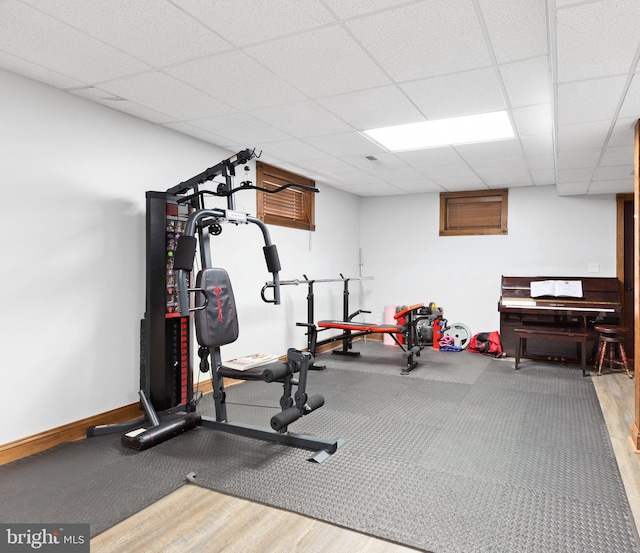 workout area featuring a drop ceiling, baseboards, and wood finished floors