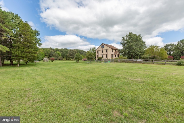 view of yard featuring a rural view, an outbuilding, fence, and a shed