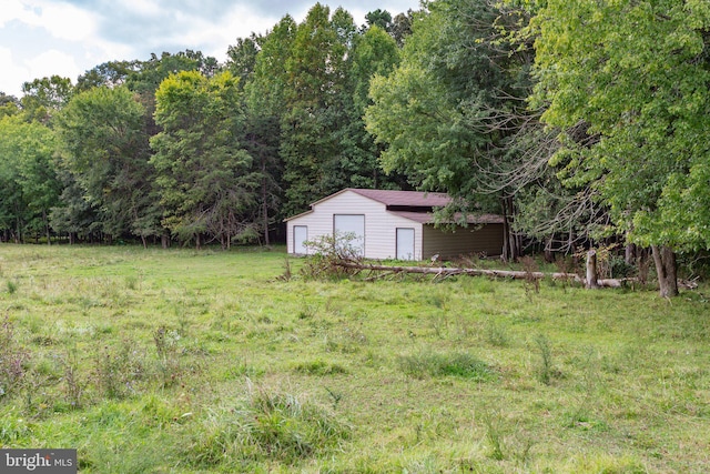 view of yard featuring a detached garage, an outbuilding, and a wooded view