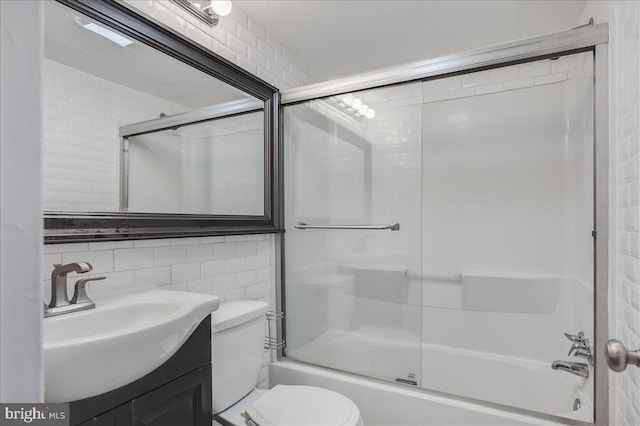 full bath featuring decorative backsplash, toilet, combined bath / shower with glass door, vanity, and tile walls