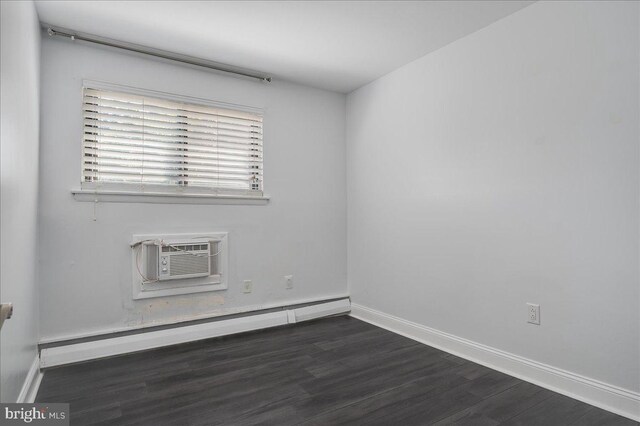 spare room featuring a baseboard heating unit, a wall mounted air conditioner, and dark hardwood / wood-style flooring