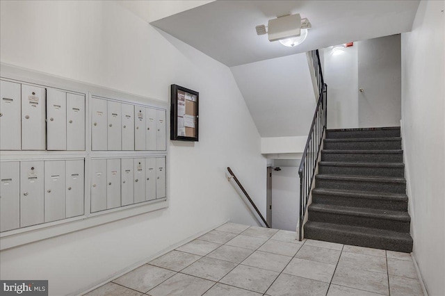 stairway featuring tile patterned flooring, a mail area, and vaulted ceiling