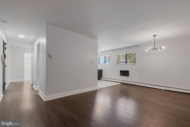 unfurnished living room with hardwood / wood-style floors, a baseboard heating unit, and a chandelier