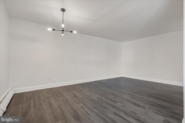 unfurnished room with a chandelier, dark wood finished floors, and baseboards