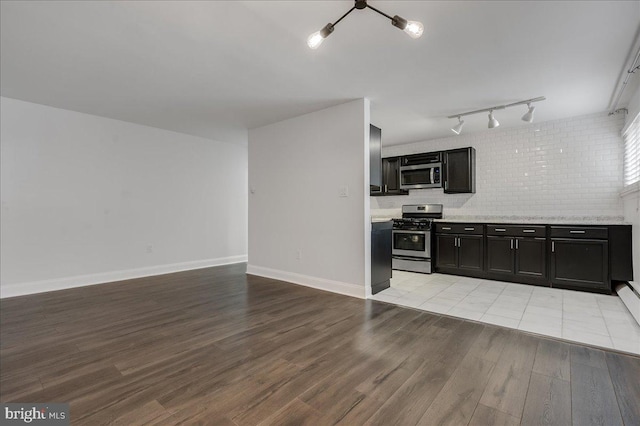 kitchen with track lighting, backsplash, light tile patterned flooring, and stainless steel appliances