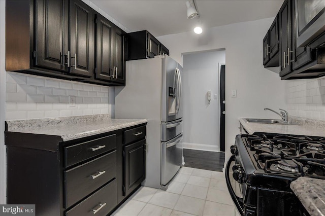 kitchen with light tile patterned floors, a sink, stainless steel refrigerator with ice dispenser, backsplash, and gas range oven