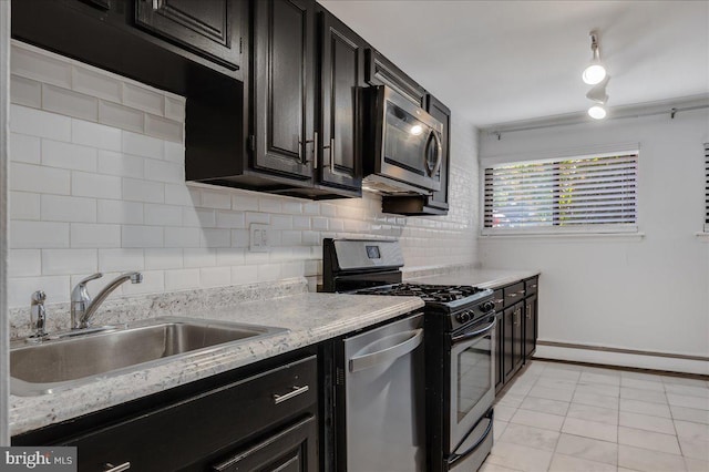 kitchen featuring appliances with stainless steel finishes, a sink, light stone counters, and decorative backsplash