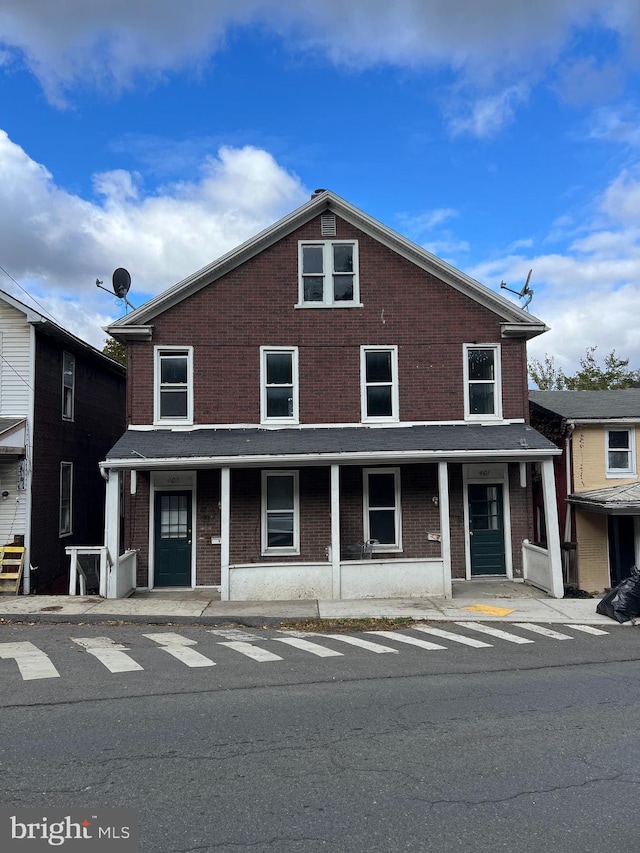 townhome / multi-family property with a porch and brick siding