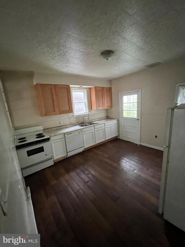 kitchen featuring light countertops, dark wood-type flooring, a sink, a textured ceiling, and white appliances