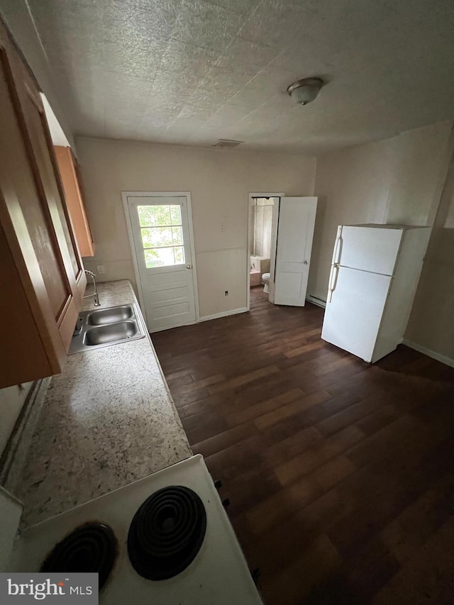 kitchen with dark wood-style floors, a textured ceiling, a sink, and baseboards