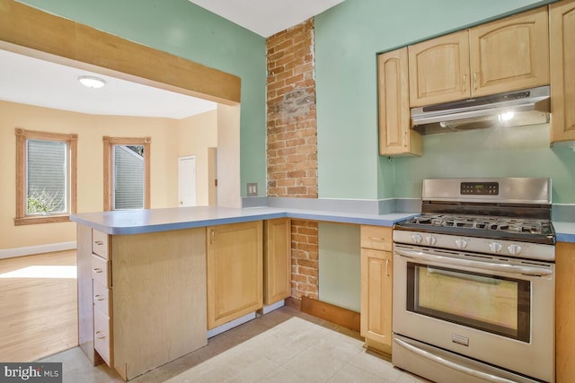 kitchen featuring kitchen peninsula, stainless steel gas range oven, light brown cabinetry, and light wood-type flooring