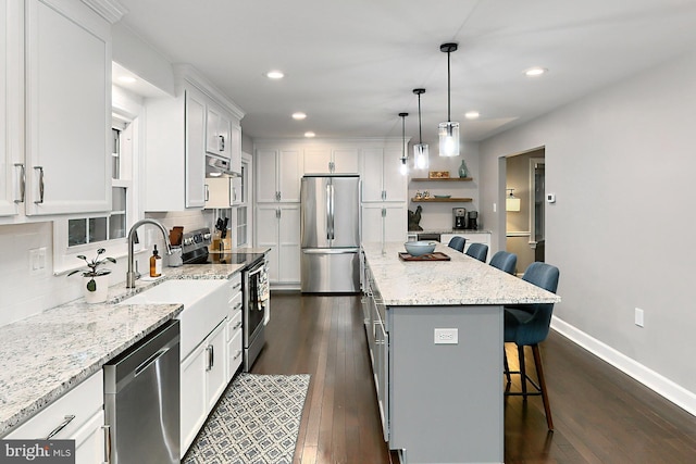 kitchen featuring a kitchen island, white cabinetry, appliances with stainless steel finishes, a kitchen breakfast bar, and dark hardwood / wood-style floors