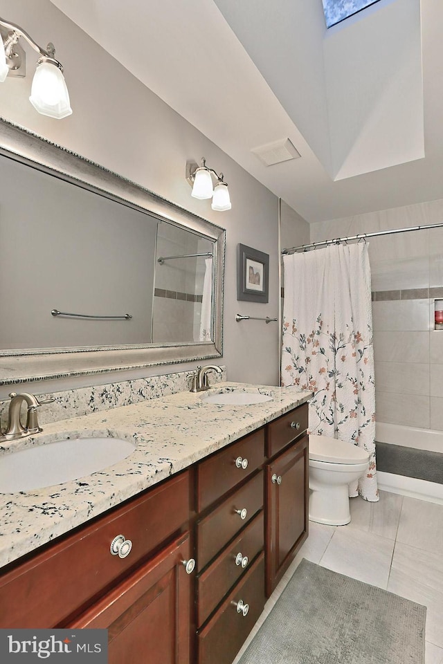 bathroom featuring a skylight, vanity, toilet, and tile patterned floors